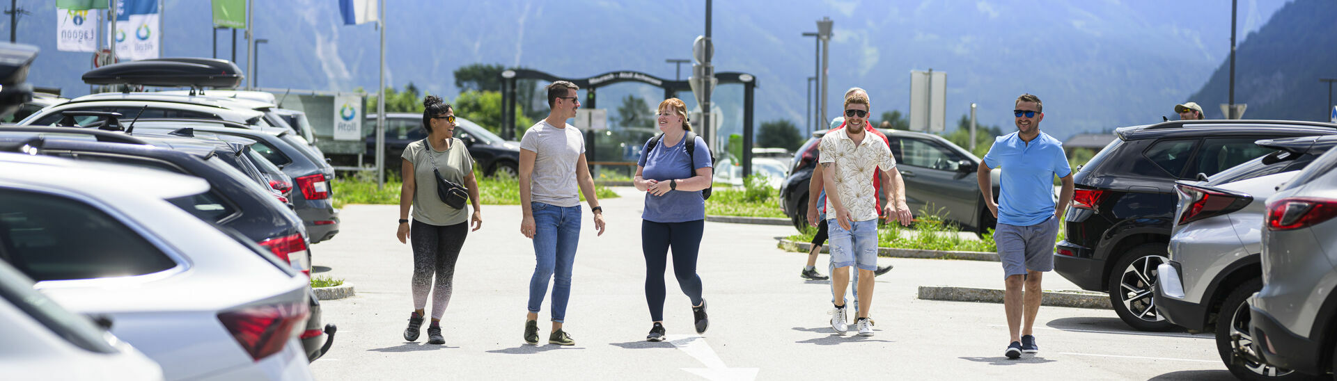 Freunde gehen beim Parkplatz des Atoll Achensee gemeinsam zum Auto.}